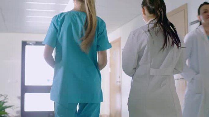 在医院里，护士和医生穿过走廊的后视图镜头。医院工作人员。