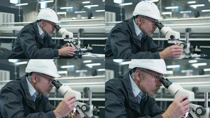 高级工程师正在工厂的显微镜下检查细节。