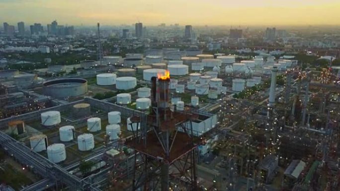 城市日出时带有燃烧火炬，储罐的化工或炼油厂的鸟瞰图