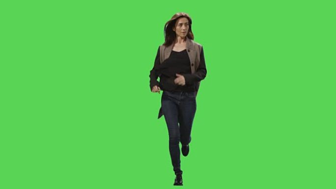 穿着外套的休闲黑发女性在背景的模拟绿色屏幕上奔跑。