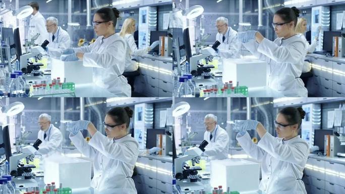 医学研究科学家打开冰箱盒子取出带有样品的培养皿并对其进行检查。她在一个繁忙的现代化实验室中心工作。