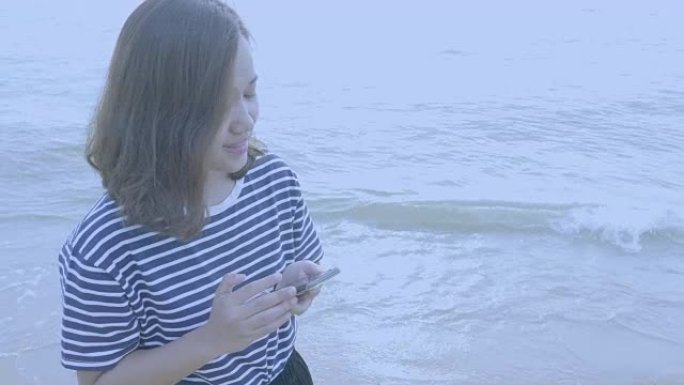 在海洋海滩拥有智能手机的亚洲女性