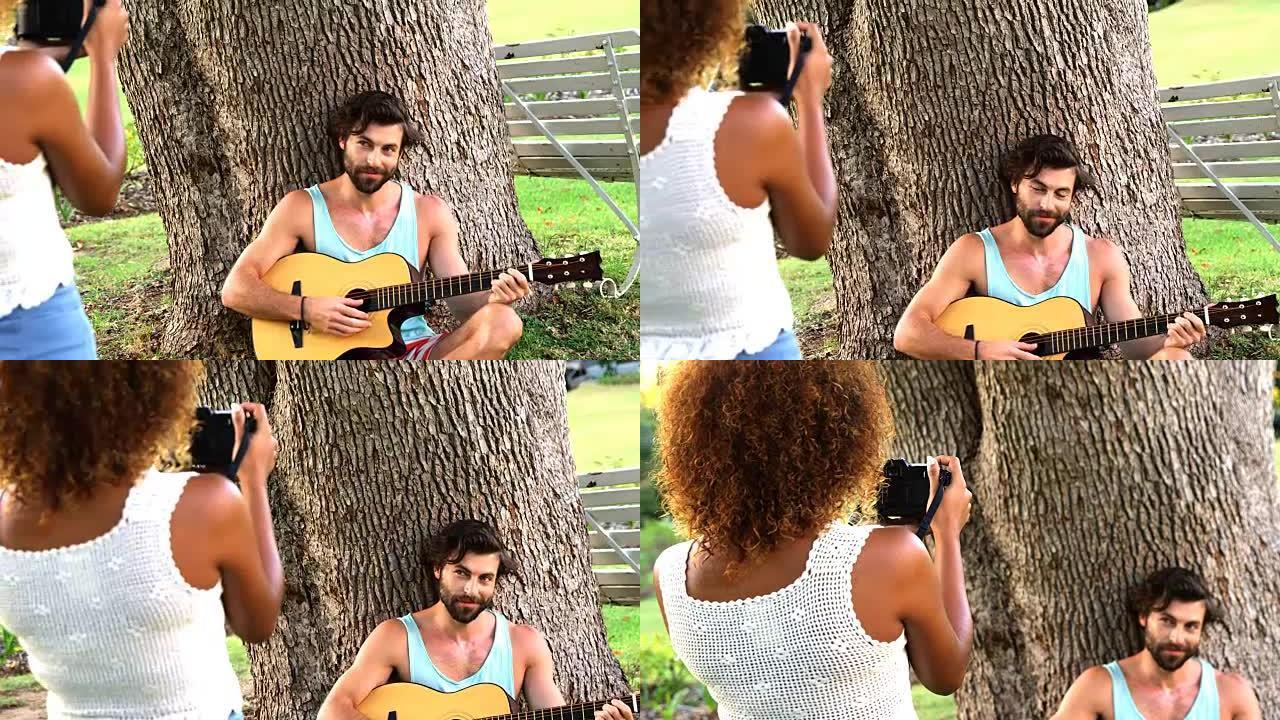 女人给一个弹吉他的男人拍照