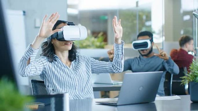 戴着虚拟Rreality耳机的女性虚拟现实工程师/开发人员与同事一起创建内容。聪明的年轻人从事增强和