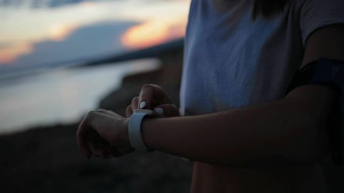 活跃的女性使用智能手表监控日落时的活动表现