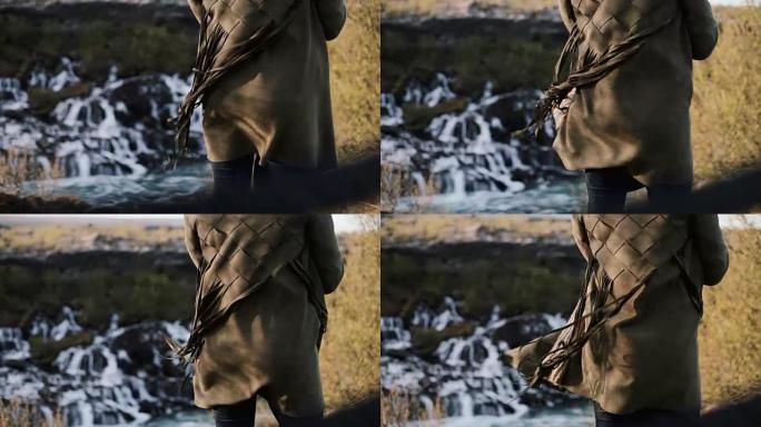 冰岛巴纳福斯瀑布和女性背部的特写镜头。年轻女子夹克的流苏随风飘扬