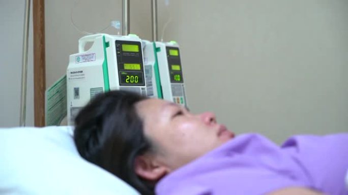 卧床不起的女性患者躺在病床上，术后恢复时接受输液。