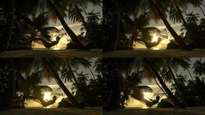 马尔代夫天堂岛异国海滩金色日落时吊床上美丽女性放松的剪影