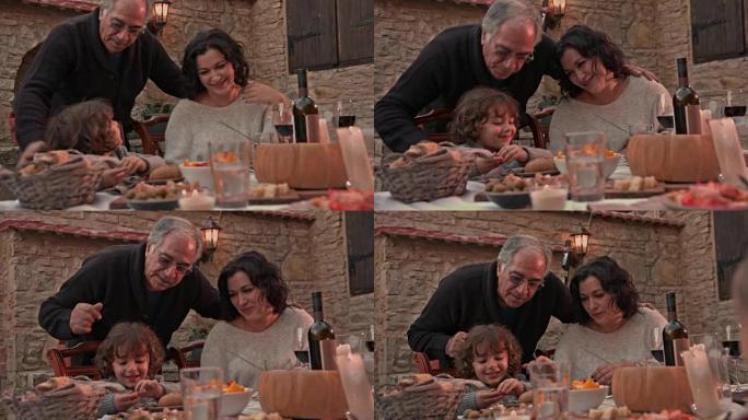祖父在餐桌上亲吻和拥抱祖母和孙子