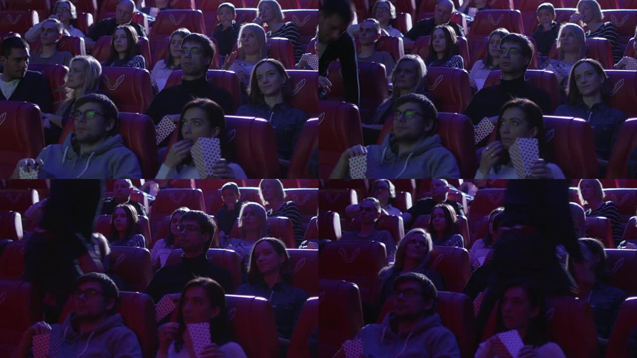 当人们在电影院观看电影放映时，一名男子从座位上退出。