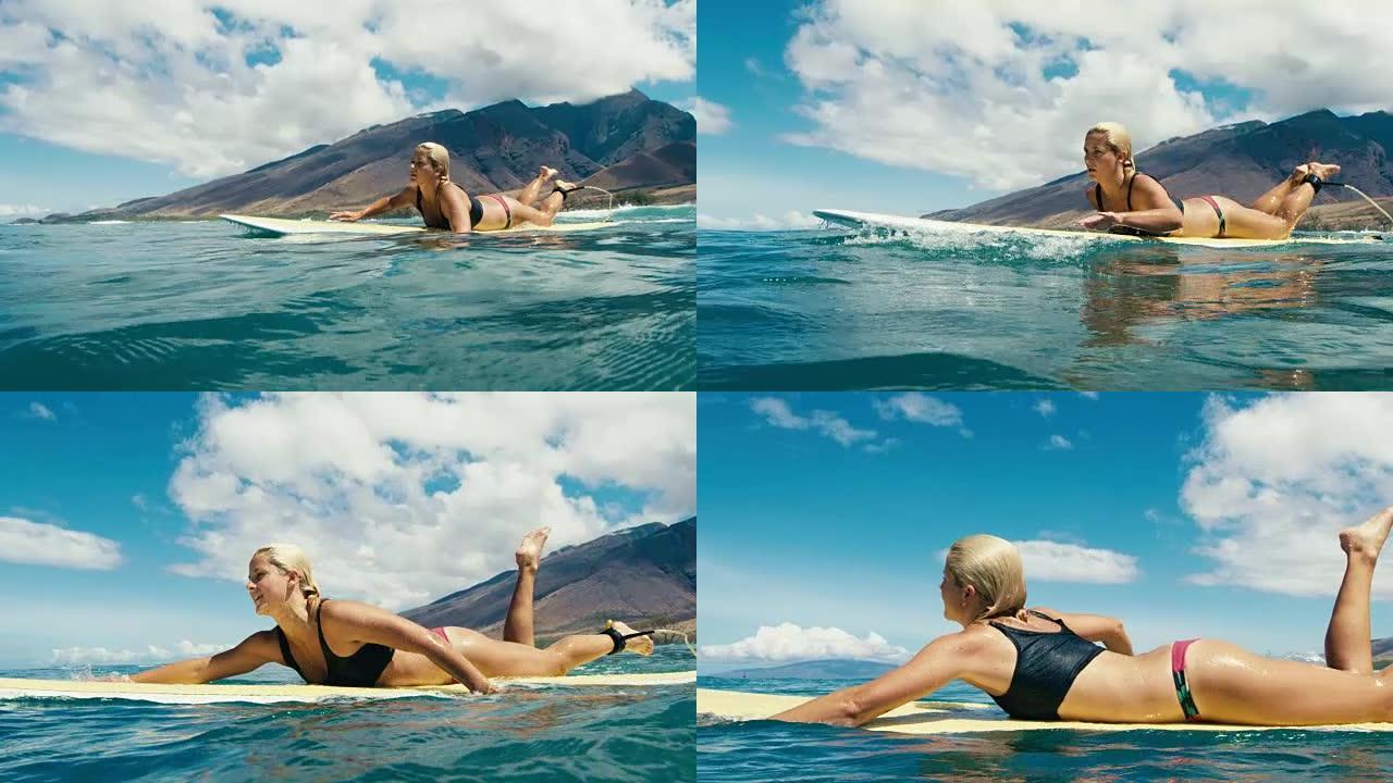 美丽的女孩在蓝色海浪上划着冲浪板