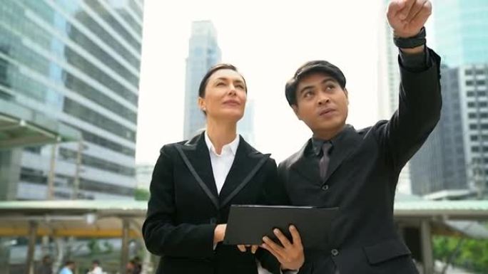 商人和女商人一起讨论使用平板电脑的业务绩效。