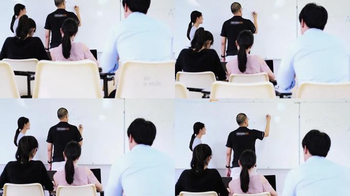 青少年在教室里从白板上的老师那里学习，学生们坐下来听老师的话。