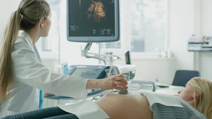 在医院，孕妇进行超声/超声筛查/扫描，产科医生在计算机屏幕上检查健康婴儿的照片。快乐的未来母亲与医生