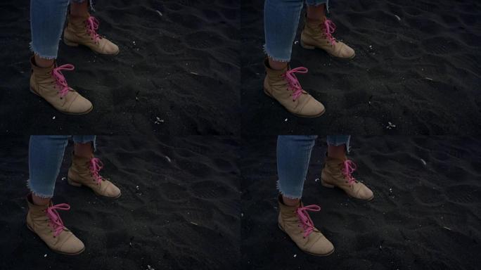 走在黑沙上。鞋子上的特写