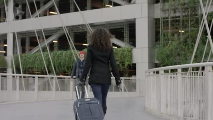 一名年轻女子拉着她的手提箱与丈夫重新团聚