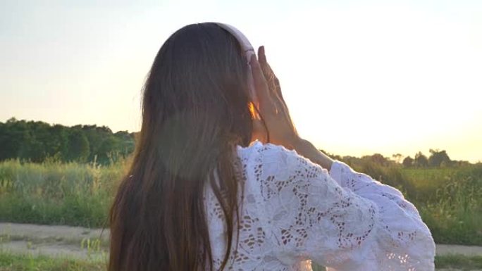 在一个阳光明媚的日子里，一个女人正穿着白色连衣裙走在麦田上，戴着草帽在自然背景概念生活方式生态环境快
