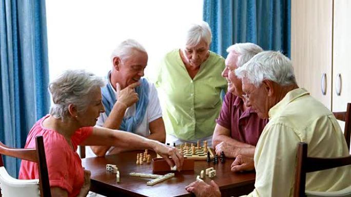 老年人下棋，一个微笑的女人与他们交谈