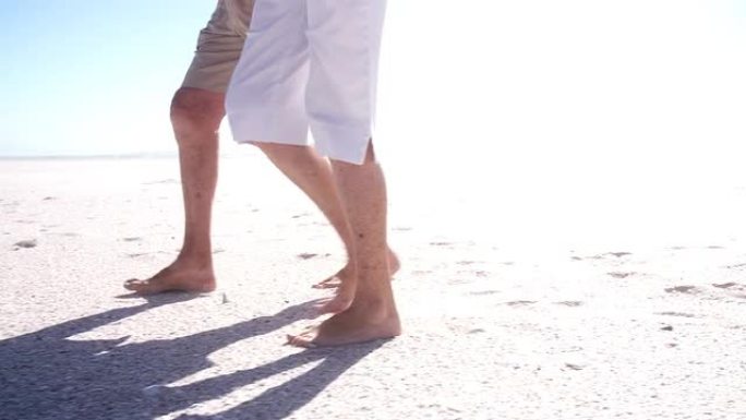 老年夫妇在沙滩上行走的腿和脚的特写