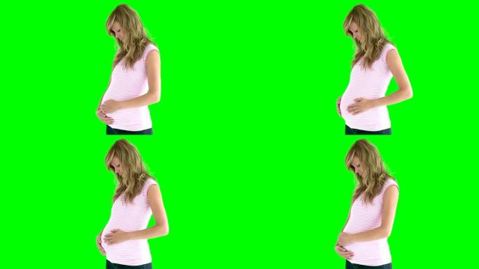 年轻女子在绿色背景下期待婴儿