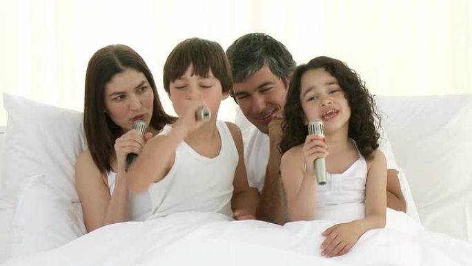 快乐的父母和孩子在床上唱歌