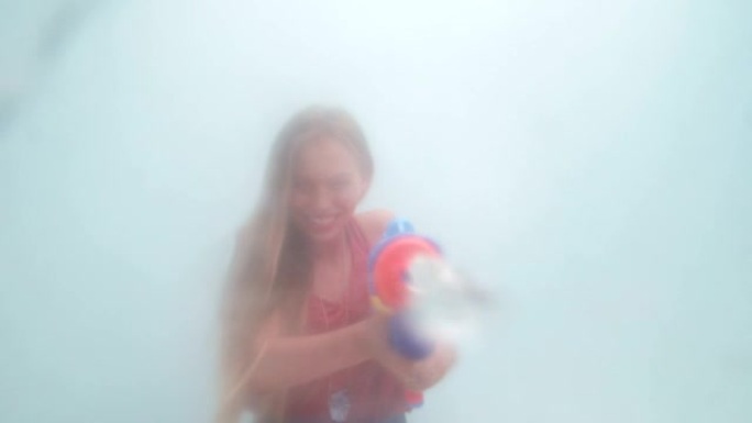 有趣的女孩用水枪喷洒相机