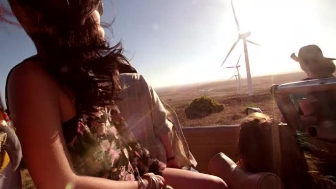 时髦女孩在公路旅行中看着汽车上的风力涡轮机
