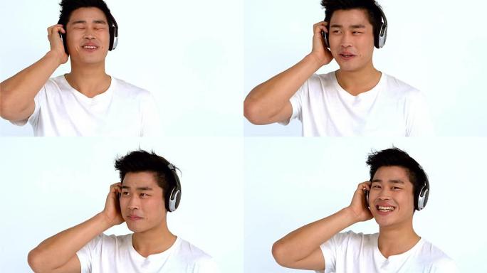 微笑的亚洲男子戴着耳机听音乐
