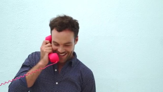可爱的时尚男人在粉色电话上说话