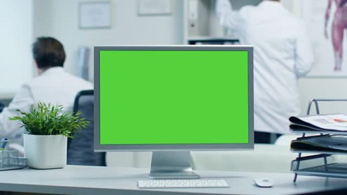 绿屏显示器的特写。医生处理文件夹，助手通过电话与患者交谈。在明亮现代的医生办公室拍摄。