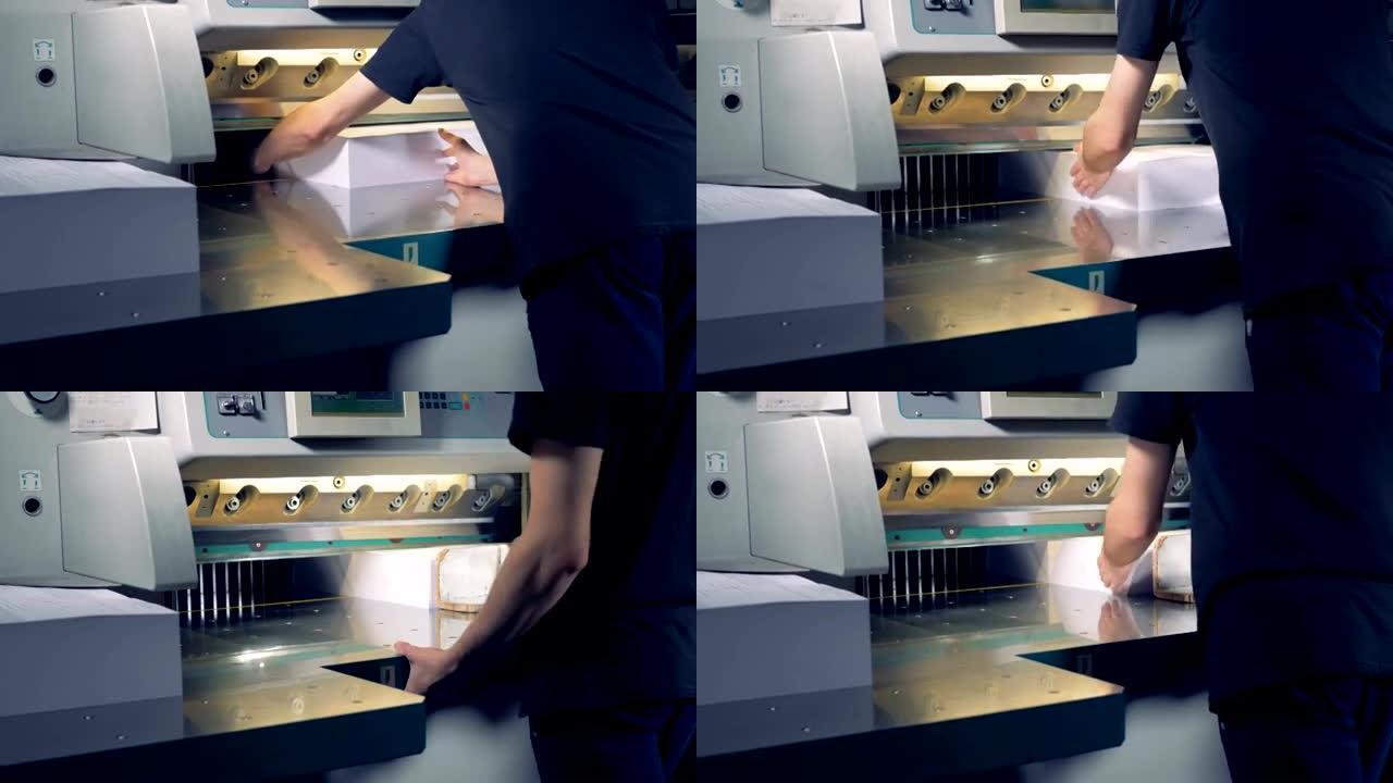 一名员工正在将两大堆纸放在切刀下，将它们分为四个部分。