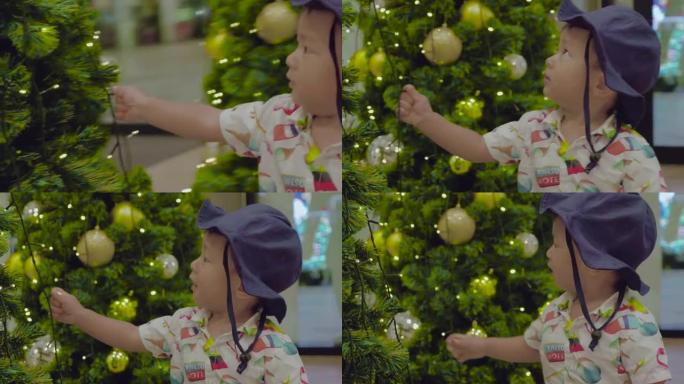 亚洲男婴新年在圣诞树上碰球