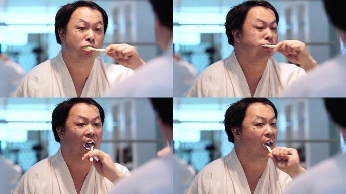 4k特写镜头亚洲男子早上在豪华酒店卧室，生活方式和休闲概念醒来时，在镜子前的浴室用牙刷刷牙