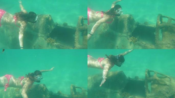 水下: 年轻女子探索飞机的残余物并看着相机。