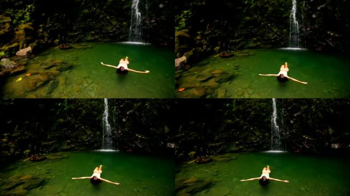 美丽的女孩漂浮在瀑布下