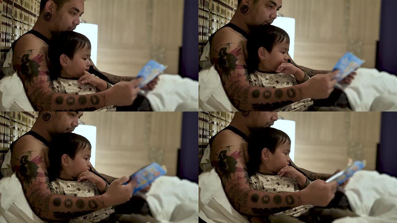 年轻的父亲和小儿子躺在家里的床上，在睡觉前读童话书