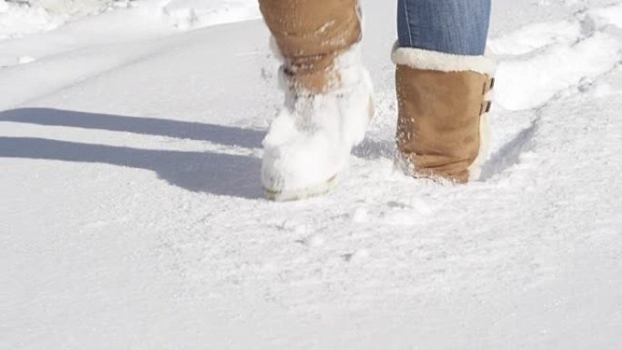 特写: 无法识别的女孩穿着冬靴踩着新鲜的未触及的雪