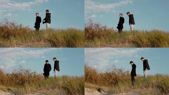 两个年轻人正从沙丘上聊天和微笑着走下来