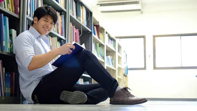 亚洲男大学生在图书馆阅读地板上进行学习研究。