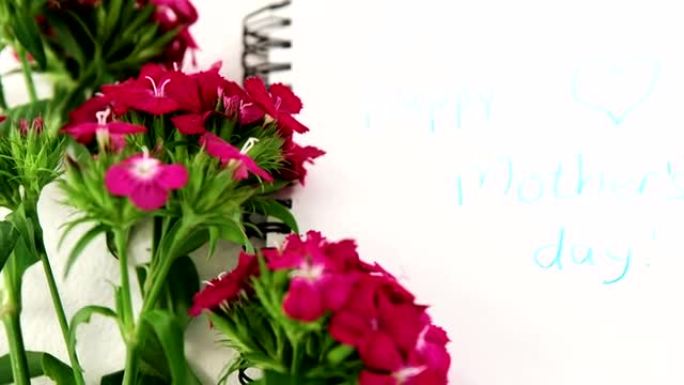 螺旋书上的粉红色花朵，带文本母亲节快乐信息