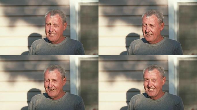 特写镜头的老人微笑着看着镜头，笑着站在太阳面前的退休男性。4K