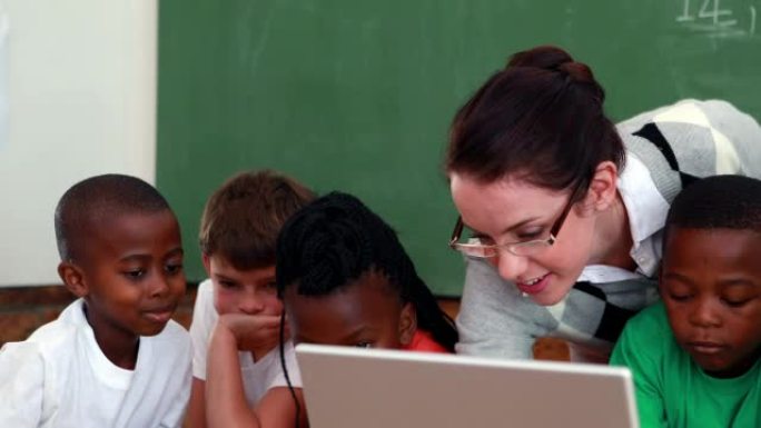 学生和老师在教室里看着笔记本电脑