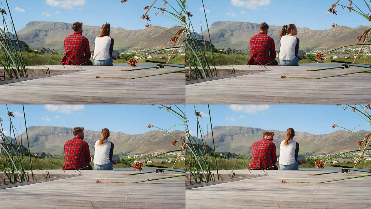 夫妇坐在湖边和山边的码头上，后视图