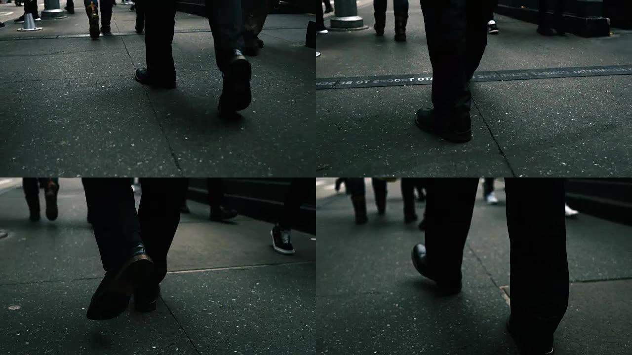 在一个繁忙的大城市人行道上行走的人的腿的特写镜头之后。