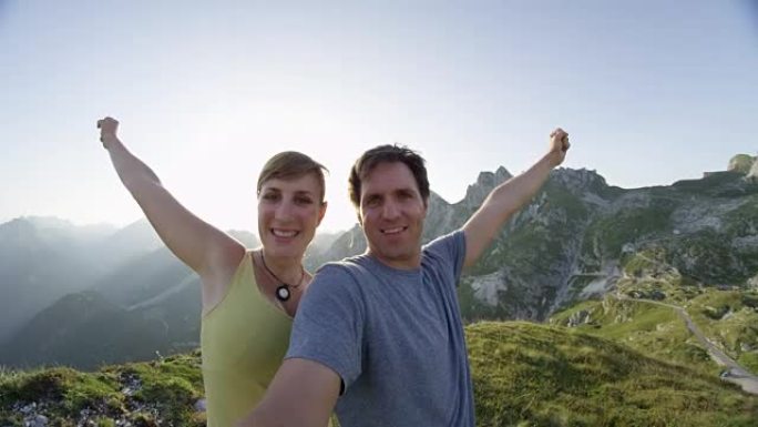 肖像: 微笑的徒步旅行夫妇在高高的岩石山顶上伸出双臂
