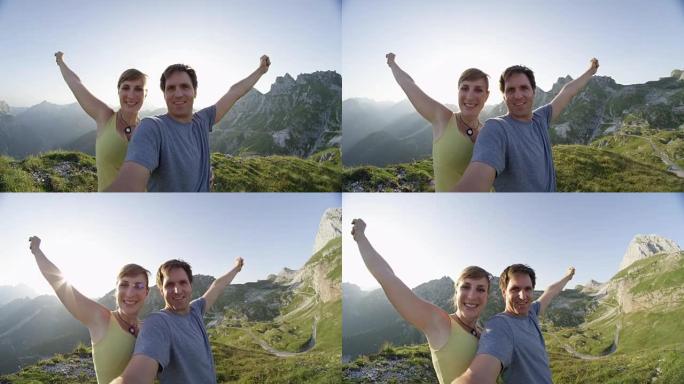 肖像: 微笑的徒步旅行夫妇在高高的岩石山顶上伸出双臂