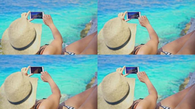 穿着比基尼的女人在阳光明媚的夏日蓝色海洋中使用照相手机