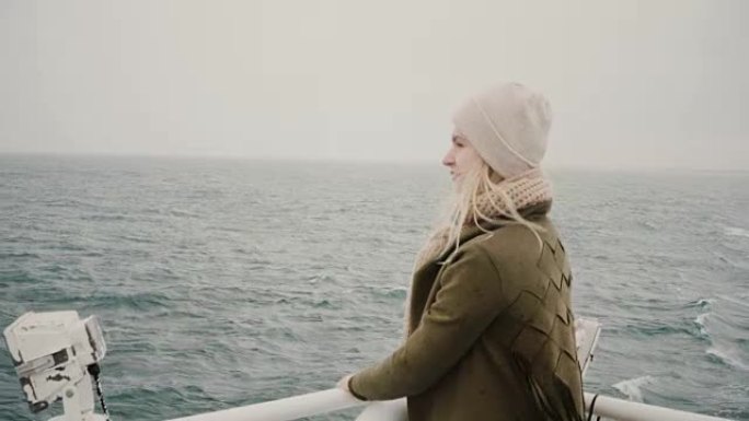 年轻的金发女子站在船上，渴望地看着大海，探索冰岛