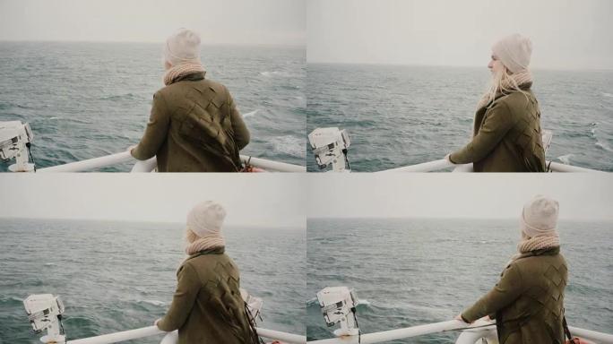 年轻的金发女子站在船上，渴望地看着大海，探索冰岛
