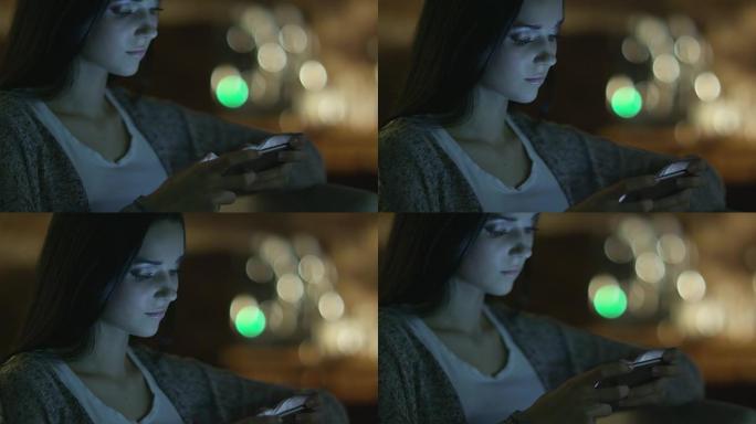 笑容灿烂的少女在晚上使用智能手机。休闲生活方式。